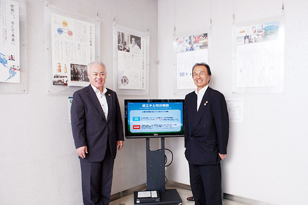 モニターを挟んで立つ、永冨社長（右）と伊藤取締役（左）